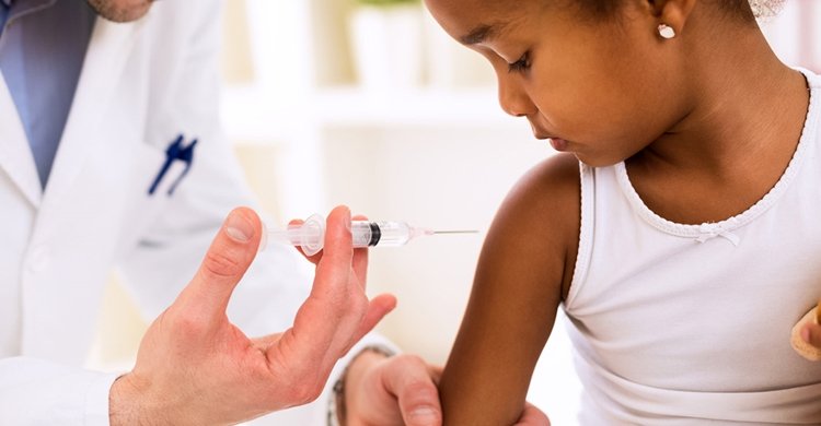 Doctor injecting vaccine to cute african girl